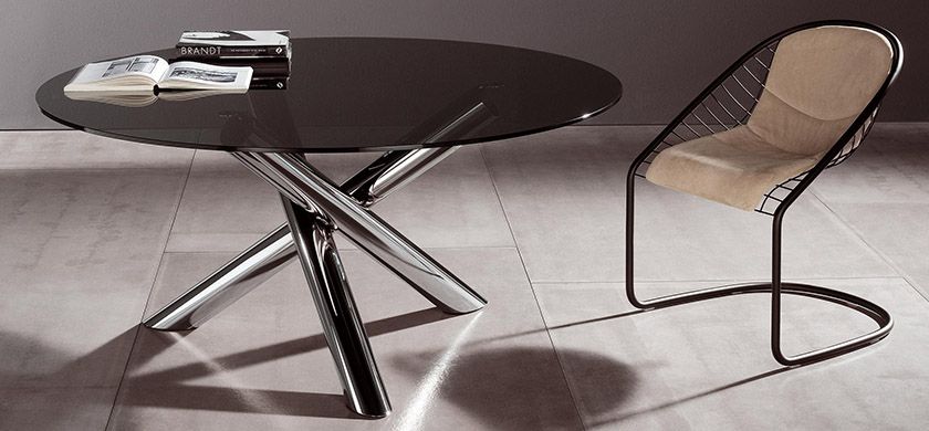 Sedia di design e tavolo in vetro con due libri sopra.